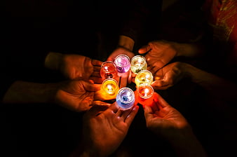 Hands holding colorful tea light candles in circle