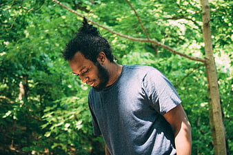 African American Man with Beard Looking Down in Forest