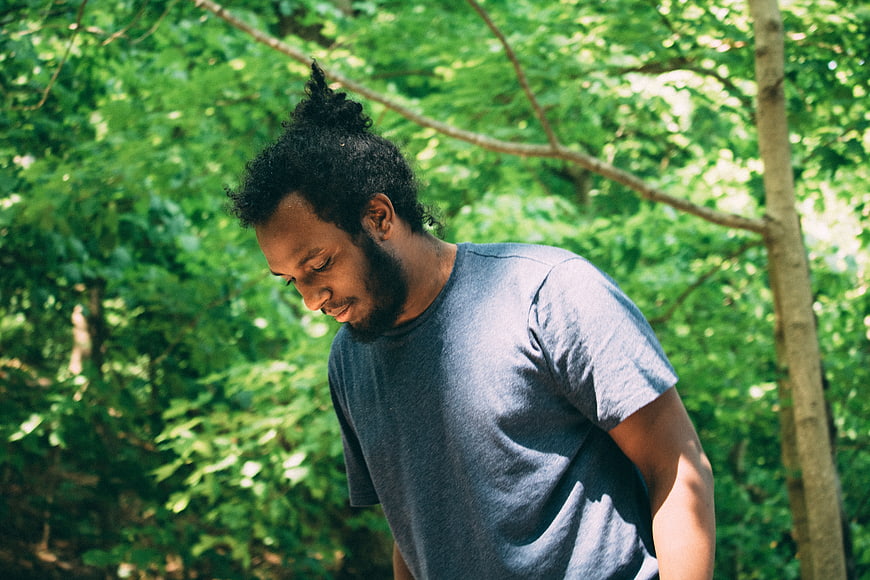 African American Man with Beard Looking Down in Forest