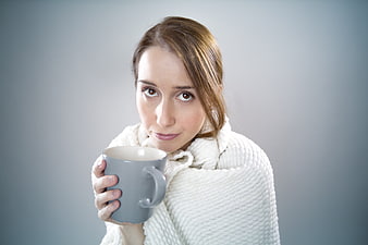 Woman wrapped in blanket holding coffee mug