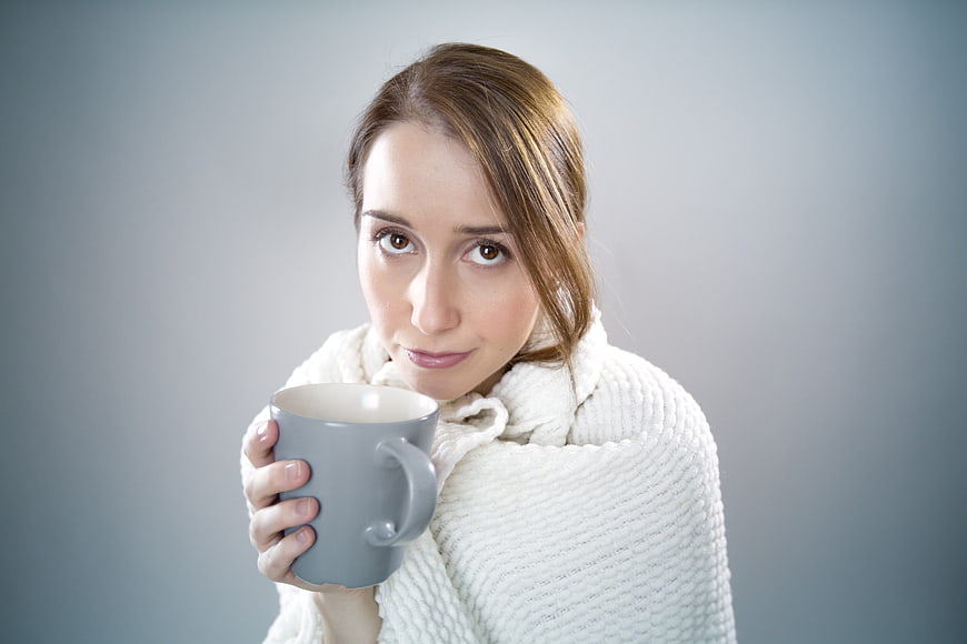 Woman wrapped in blanket holding coffee mug
