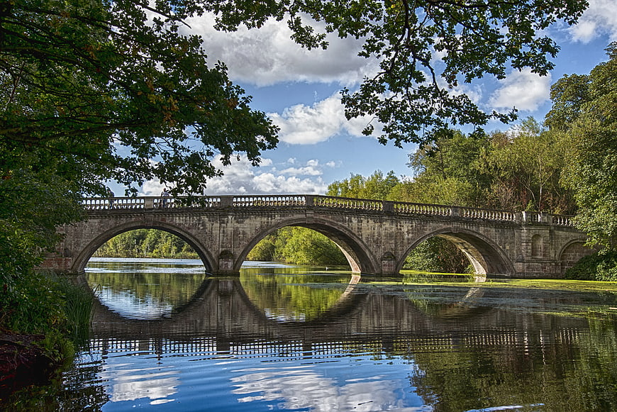 Historic stone arch bridge over calm river with reflection