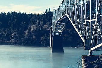 Steel truss bridge over misty river with forest background