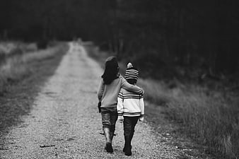 Two children walking away on a gravel road in black and white
