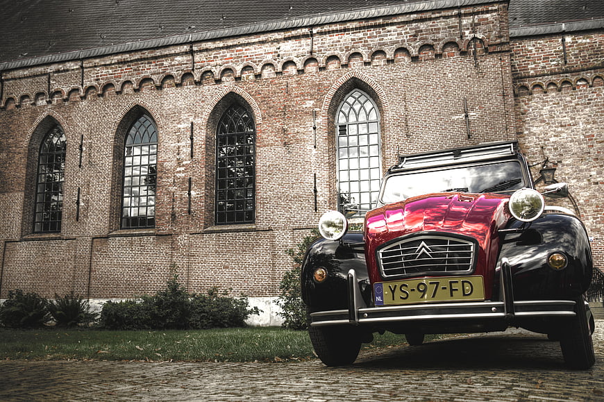 Vintage Citroën 2CV parked in front of a brick church