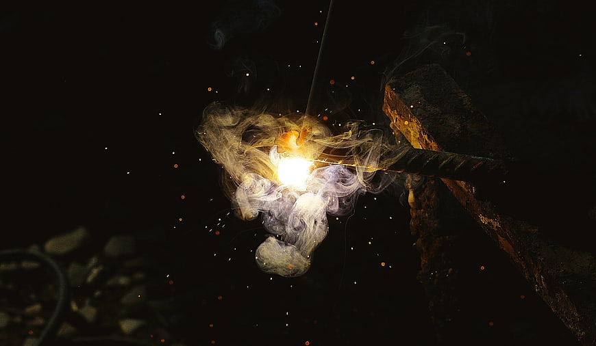 Close-up of welding sparks and smoke on dark background