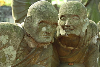Two weathered stone monk statues conversing in a Japanese temple garden
