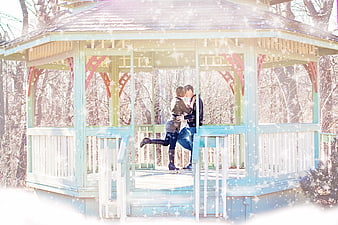 Romantic couple kissing in a winter gazebo with falling snow