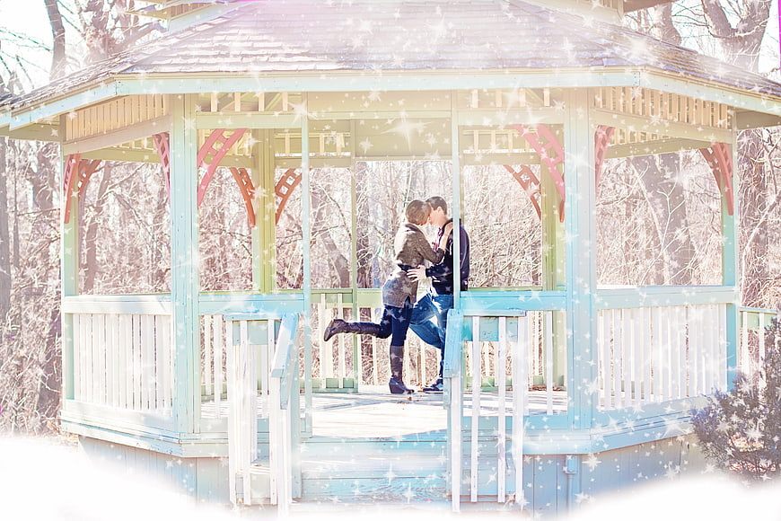Romantic couple kissing in a winter gazebo with falling snow