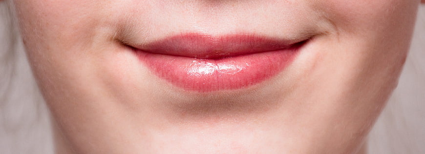 Close-up of glossy pink lips on fair skin