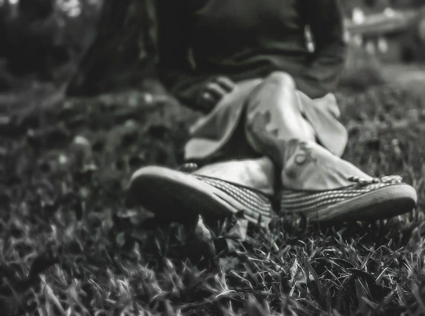 Black and white photo of woman's feet in espadrilles on grass