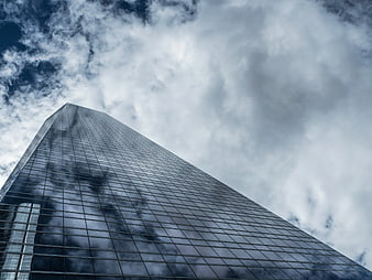 Worm's Eye View of Modern Glass Skyscraper Against Cloudy Sky