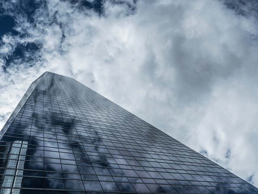 Worm's Eye View of Modern Glass Skyscraper Against Cloudy Sky