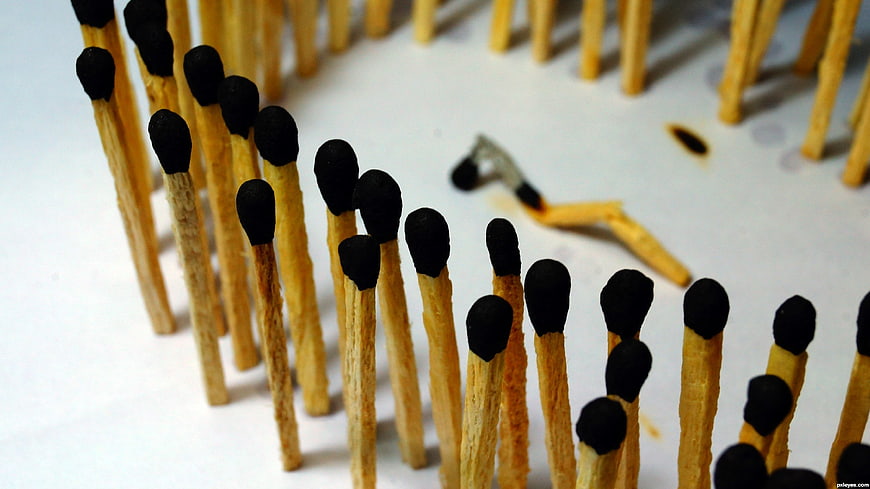 Broken matchstick standing among upright matches on white background