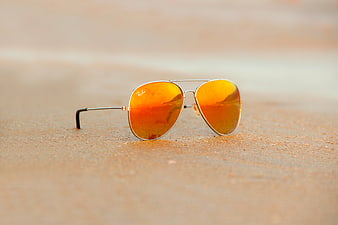 Aviator Sunglasses with Orange Lenses on Sandy Beach