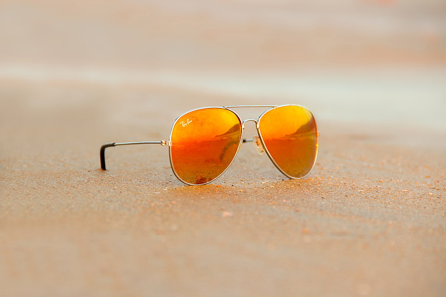Aviator Sunglasses with Orange Lenses on Sandy Beach