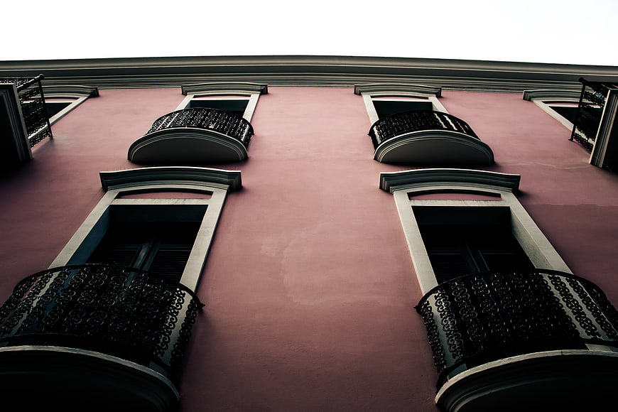 Low angle view of pink building facade with ornate balconies