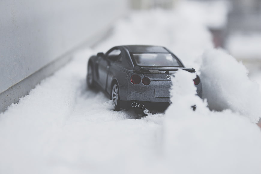 Gray toy sports car buried in snow