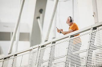 Happy Senior Man Listening to Music on Smartphone on Bridge