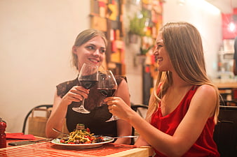 Two women toasting with red wine at a restaurant dinner