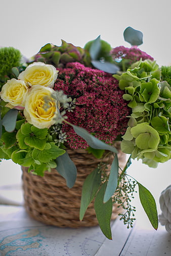 Rustic floral arrangement with yellow roses and green hydrangeas in woven basket