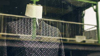 Mannequin in Patterned Shirt Behind Dirty Window
