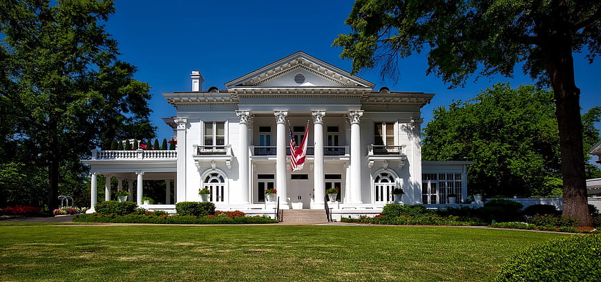 Grand white neoclassical mansion with columns and American flag