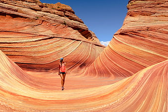 Woman hiking in The Wave sandstone formation, Arizona desert landscape