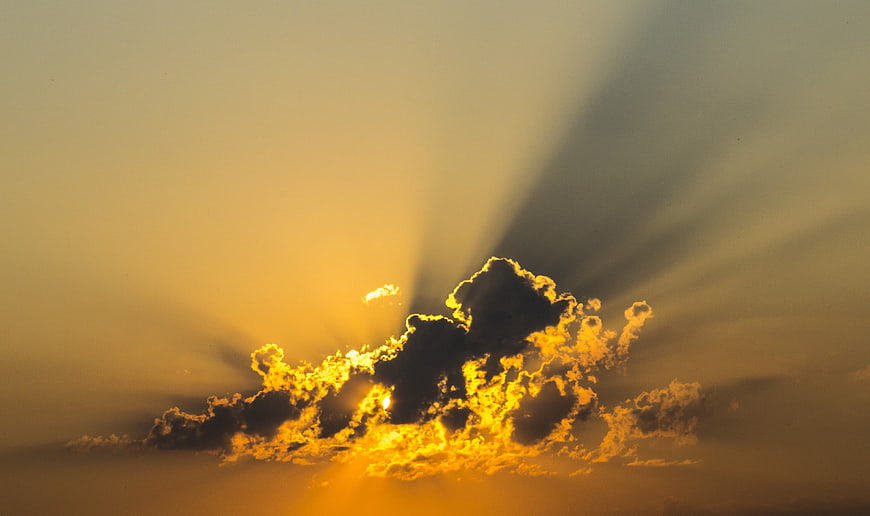 Dramatic Golden Sun Rays Bursting Through Dark Clouds at Sunset
