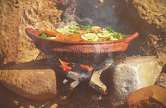 Traditional clay pot cooking vegetables over open fire outdoors