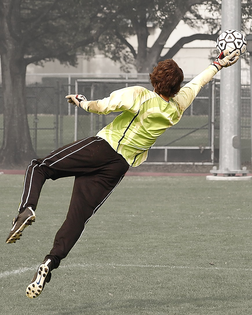 Soccer Goalkeeper Diving to Catch Ball on Field