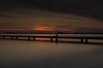 Silhouette of a pier at sunset over calm water