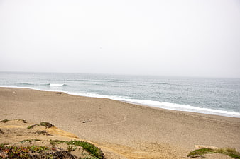 Misty coastal landscape with sandy beach and gentle ocean waves