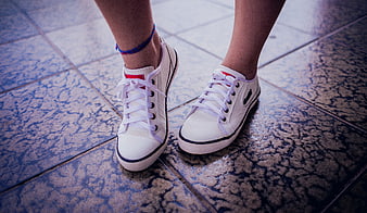 Close-up of white sneakers on tiled floor