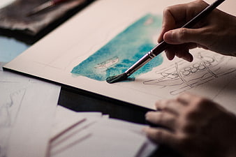 Close-up of hand painting watercolor landscape with brush