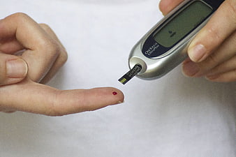 Close-up of blood glucose test with finger prick and meter