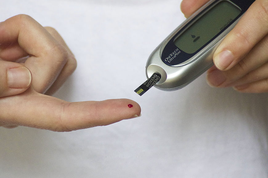 Close-up of blood glucose test with finger prick and meter