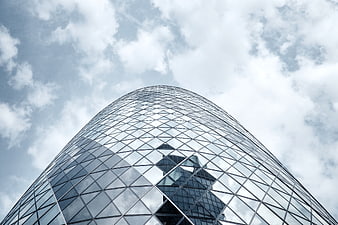Low angle view of modern glass skyscraper reflecting clouds