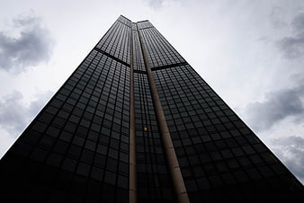 Low angle view of modern skyscraper against cloudy sky