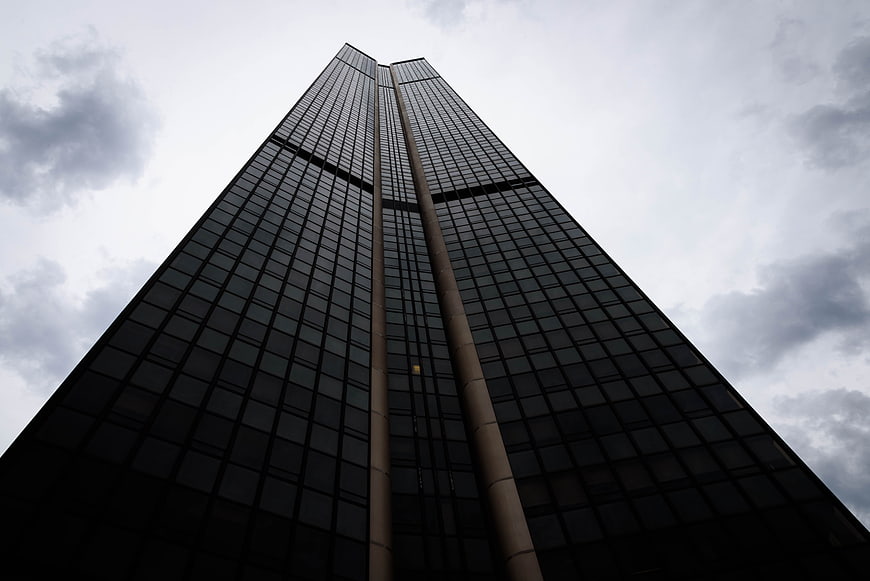 Low angle view of modern skyscraper against cloudy sky