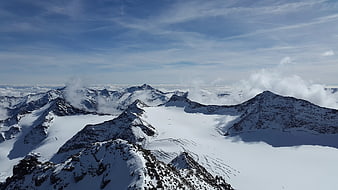 Aerial View of Snow-Covered Mountain Peaks Above Clouds