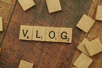 Vlog spelled with wooden Scrabble tiles on textured background