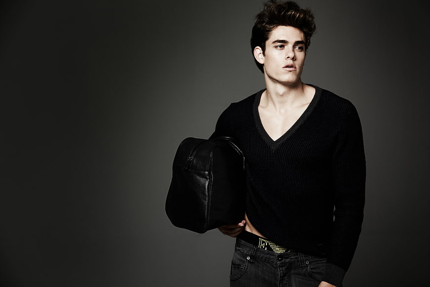 Handsome man holding black leather bag in studio
