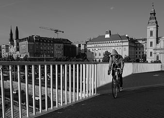 Man Cycling on Urban Bridge in Black and White