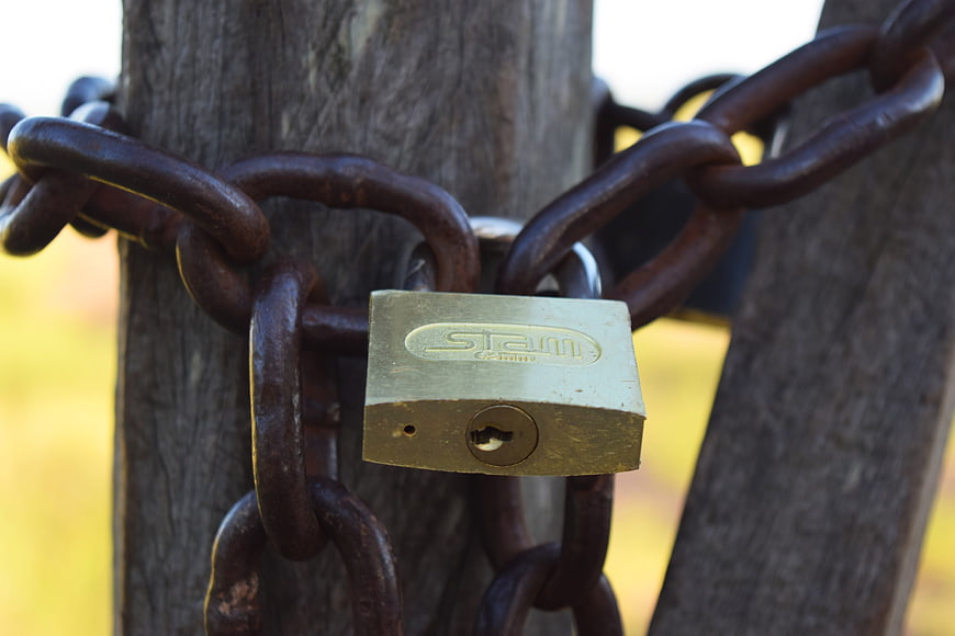 Rusty Chain and Brass Padlock on Wooden Post