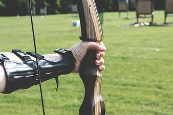 Close-up of hand holding wooden recurve bow outdoors