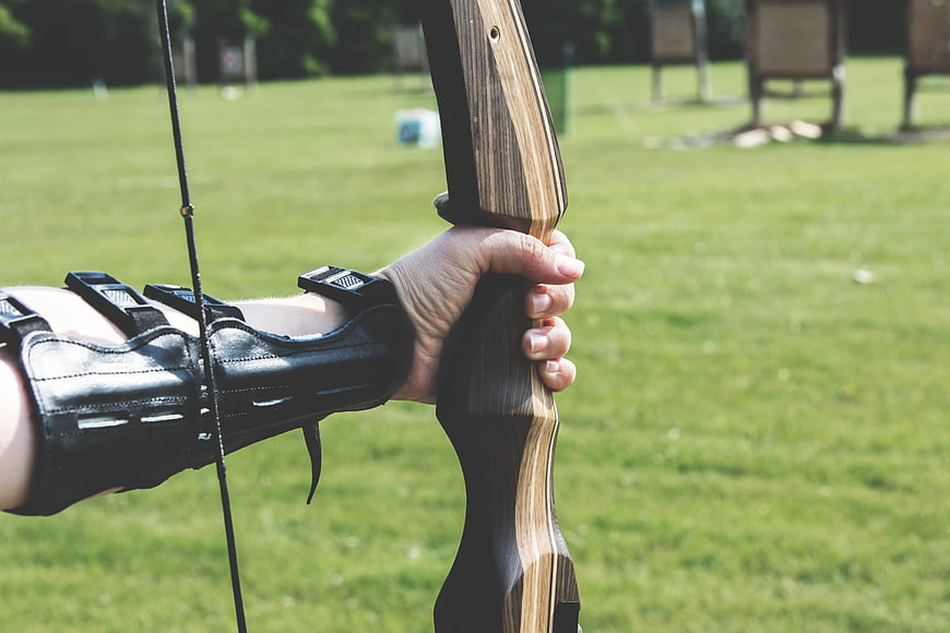 Close-up of hand holding wooden recurve bow outdoors