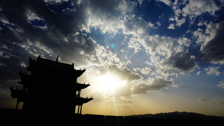 Silhouette of Jiayuguan Fort against dramatic sunset sky