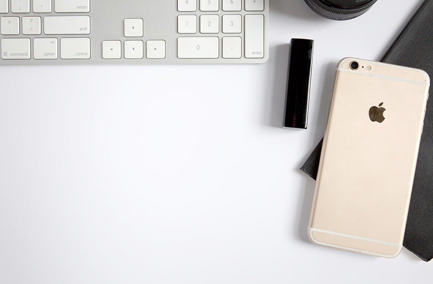 Minimalist workspace with gold smartphone, keyboard, and notebook