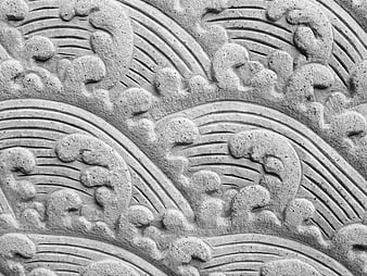Close-up of gray stone carving with wave and cloud patterns